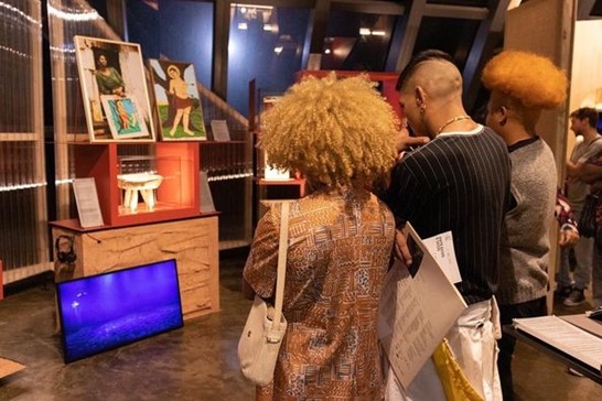 pessoas observando exposições artísticas no museu paranaense